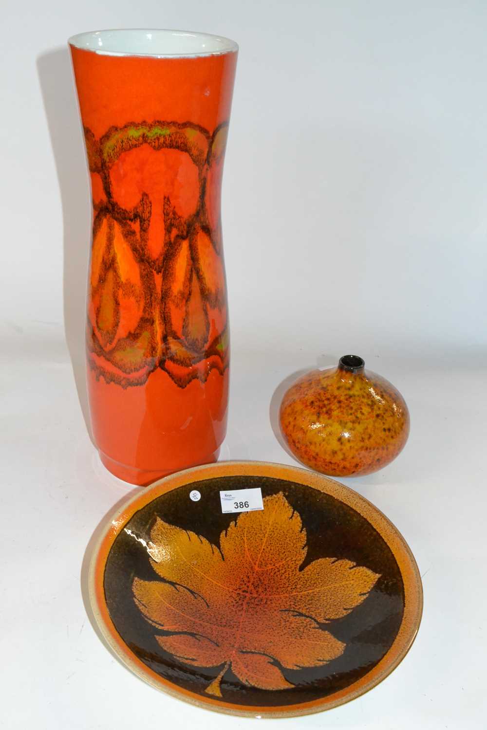 A group of three Poole pottery wares comprising a large red glazed Adelphis type vase, a fern leaf