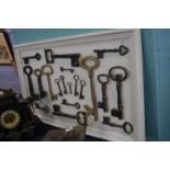 A display board containing a collection of various vintage iron and brass keys containing a