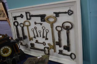 A display board containing a collection of various vintage iron and brass keys containing a