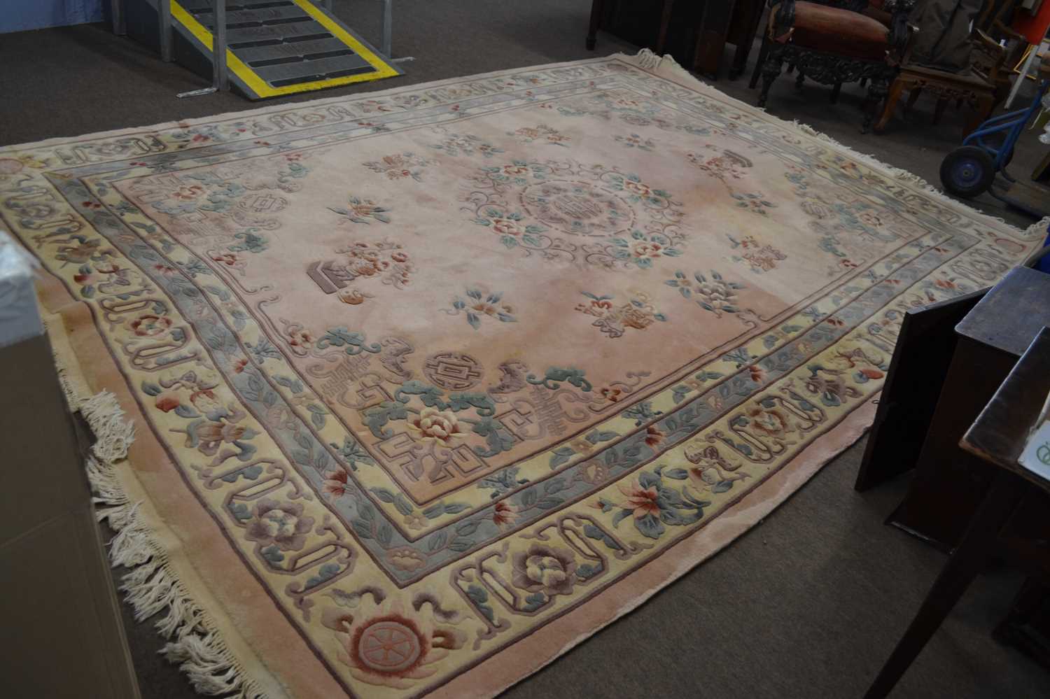 A large Chinese pink washed wool carpet decorated with floral detail and motifs