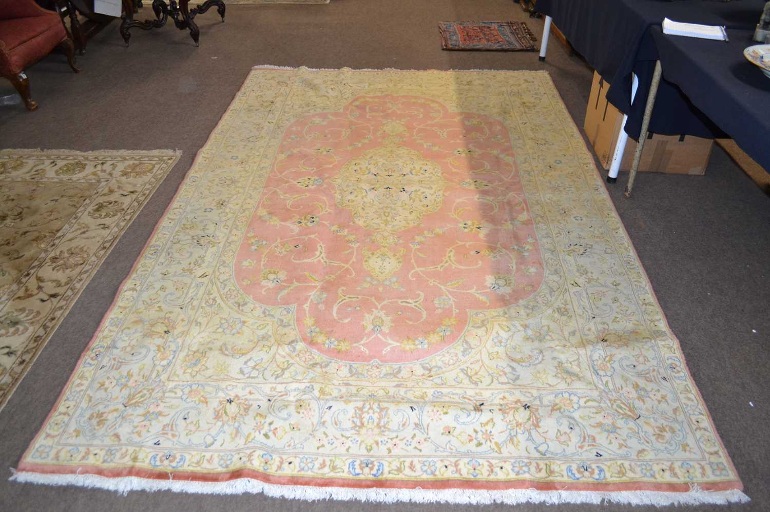 A fine Tabriz carpet with a pale border surrounding a pink central panel, decorated throughout