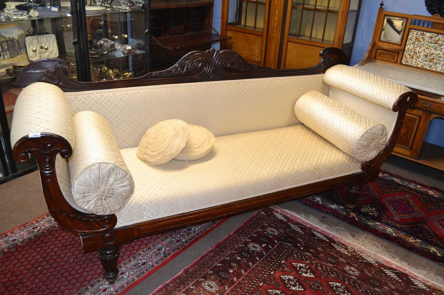 A large late regency mahogany framed sofa with scrolled ends and bolster cushions supported on