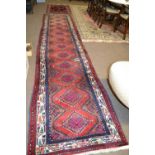 A 20th Century Turkish wool runner carpet decorated with diamond medellions in rust, blue, beige and