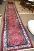 A 20th Century Turkish wool runner carpet decorated with diamond medellions in rust, blue, beige and