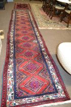 A 20th Century Turkish wool runner carpet decorated with diamond medellions in rust, blue, beige and