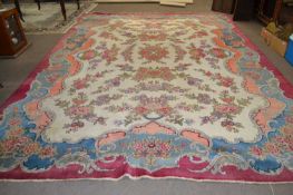An early 20th Century wool carpet with all over rose decoration and large central cartouche
