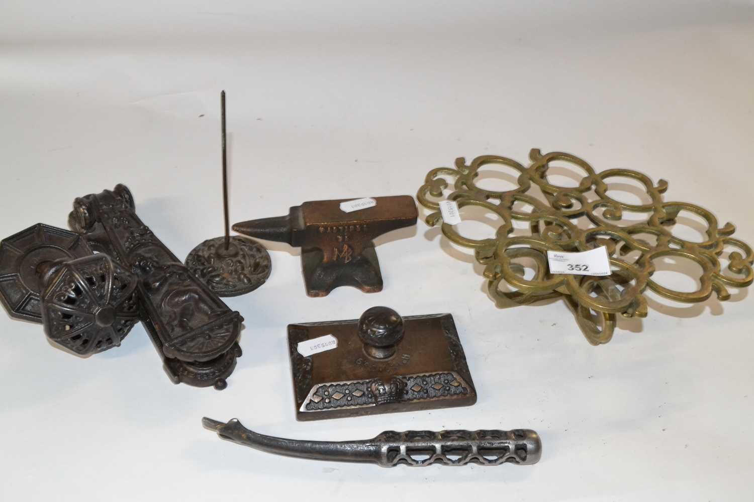 Mixed group of metal wares comprising a pierced brass trivet, a Victorian iron door knocker, a