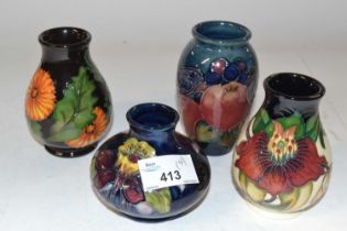 A group of four small baluster shape Moorcroft vases, one with an orchid design on blue ground, a