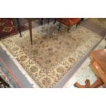 A 20th Century wool floor rug decorated with a stylised floral design on a cream and taupe