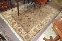 A 20th Century wool floor rug decorated with a stylised floral design on a cream and taupe