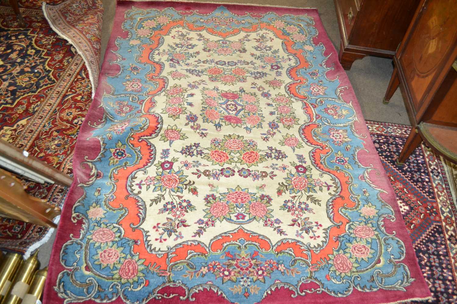 An early 20th Century wool rug decorated with a rose design to central cartouche and borders, approx