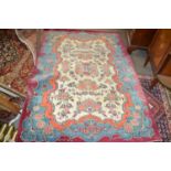 An early 20th Century wool rug decorated with a rose design to central cartouche and borders, approx