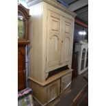 A Victorian stripped pine four door cupboard, the top section with two large panelled doors over a