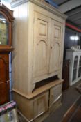 A Victorian stripped pine four door cupboard, the top section with two large panelled doors over a