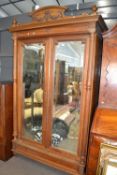 Late 19th Century continental walnut wardrobe with arched pediment, two doors with bevelled mirrored