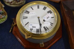 A ships clock in brass case mounted on shaped wooden base