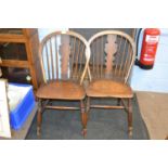 A pair of 19th Century elm seated kitchen chairs with stick and shaped splat backs, raised on turned