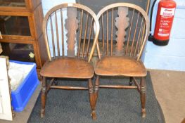 A pair of 19th Century elm seated kitchen chairs with stick and shaped splat backs, raised on turned