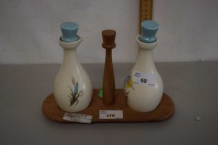 A Beswick pair of vinegar bottles on wooden stand by Beswick with floral decoration