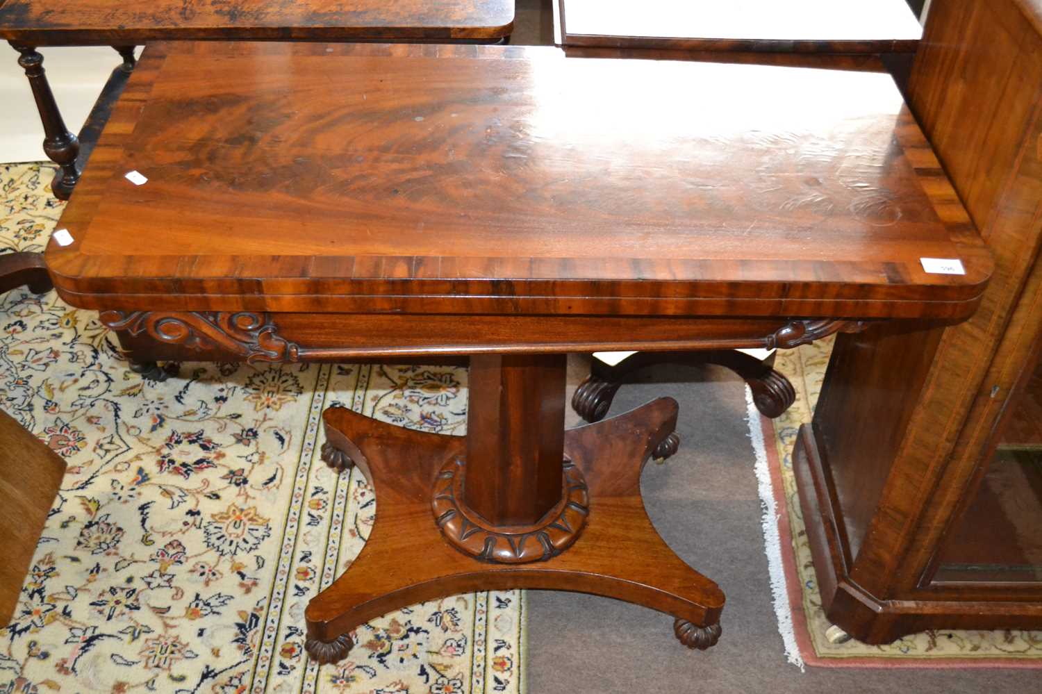 A Victorian flame mahogany veneered card table with folding and rotating baize lined top over an