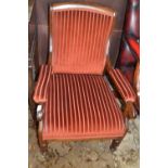 A Victorian rosewood framed and striped upholstered armchair with turned legs and casters
