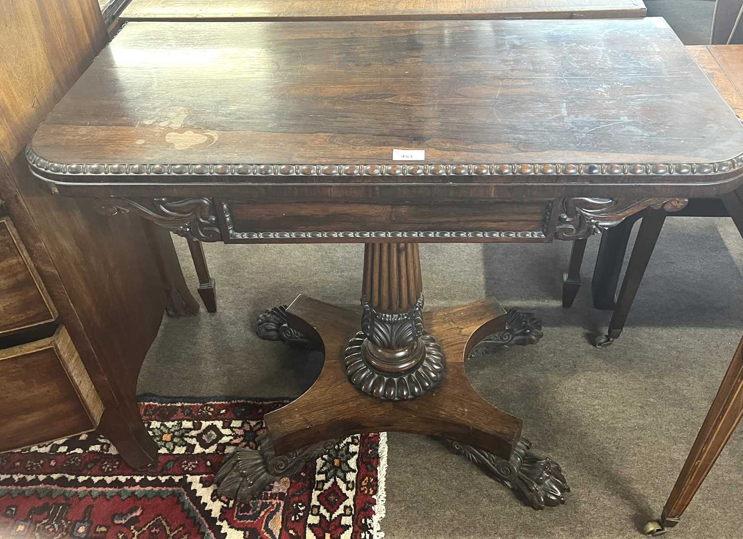 An early 19th Century rosewood card table, the top with red baize lining set on a fluted column with