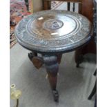 An Indian hardwood occasional table with circular carved top supported on elephant shaped legs,