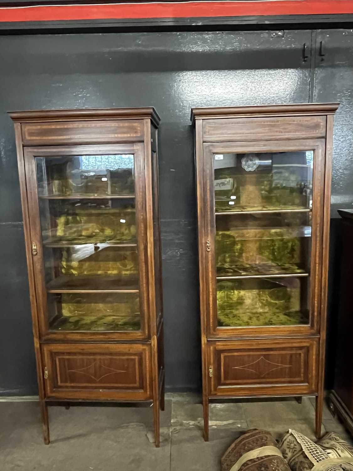 A pair of Edwardian mahogany and inlaid display cabinets with fabric lined interiors and cupboard