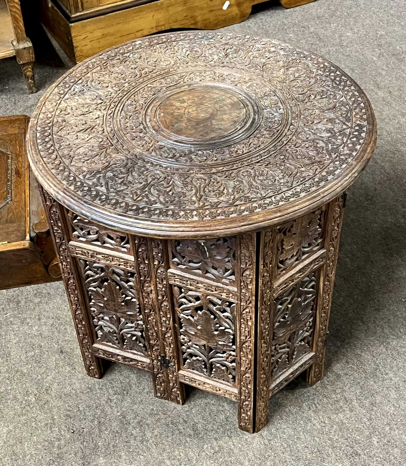 An Indian hardwood occasional table with carved circular top and pierced folding base, top 45cm