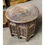 An Indian hardwood occasional table with carved circular top and pierced folding base, top 45cm