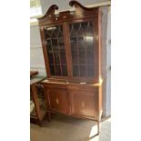 An Edwardian mahogany side cabinet with broken arch pediment over two astragal glazed doors and a