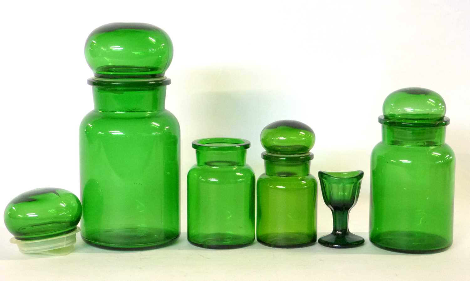 Group of green glass jars and a small eye bath