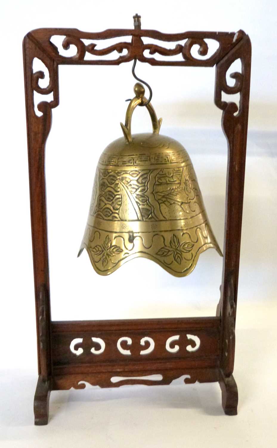 A Chinese Tibetan temple bell, engraved with dragons, with its carved hardwood stand
