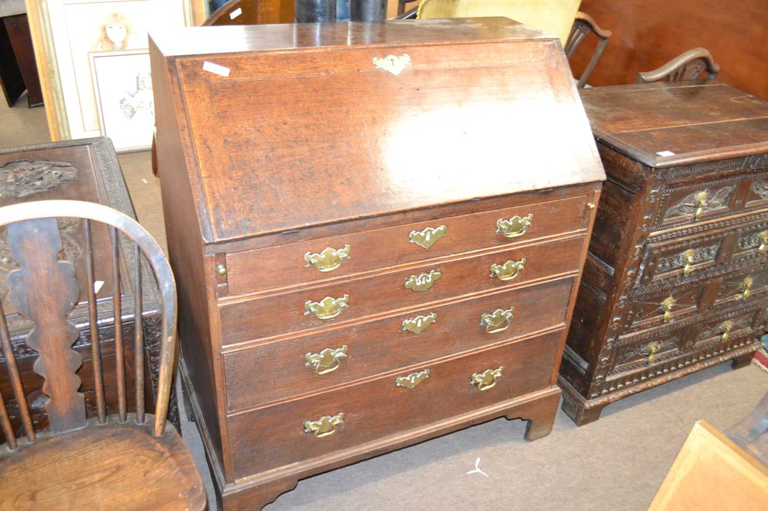 A George III oak bureau of typical form with full front opening to a fitted interior, over a four