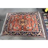 An Afghan Merino wool rug decorated with large central floral panel on a rust coloured background