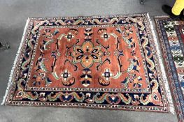 An Afghan Merino wool rug decorated with large central floral panel on a rust coloured background
