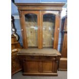 A late Victorian oak bookcase cabinet formed of two sections, top section with glazed doors, the
