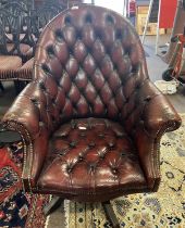 A distressed red leather Chesterfield style revolving desk chair