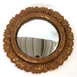 A decorative convex mirror with carved petal border