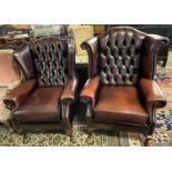 Two similar 20th Century leather button back Chesterfield type wing chairs raised on cabriole legs