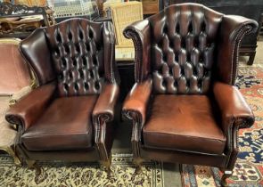 Two similar 20th Century leather button back Chesterfield type wing chairs raised on cabriole legs
