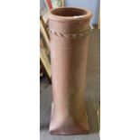 A terracotta chimney pot of tapering circular form with a square base, 93cm high