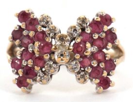 A 9ct ruby and diamond bow ring, the bow set with rubies and diamond detailing to centre, split