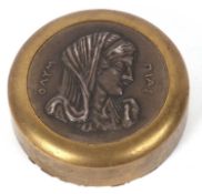 A paperweight by Ilias Lalaounis, the round brass disc with inset silver relief head, stamped '