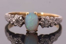 An 18ct and platinum opal and diamond ring, the central oval opal cabochon set to either side with