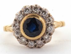 An 18ct sapphire and diamond ring, the central round sapphire in a rubover mount, surrounded by