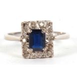 An 18ct sapphire and diamond ring, the rectangular step cut sapphire, surrounded by single cut