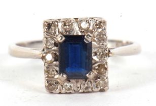 An 18ct sapphire and diamond ring, the rectangular step cut sapphire, surrounded by single cut