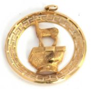 A pendant stamped 750, the round pendant with Greek key style border and set to centre with a deer