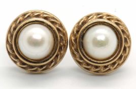 A pair of 9ct cultured pearl earrings, the round cultured pearl in a rubover mount with rope twist